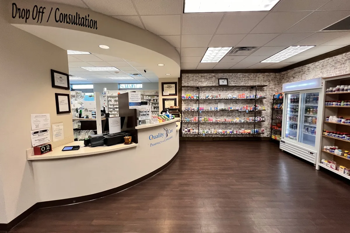 The drop off and consultation window inside Quality Care Pharmacy, with the retail floor beyond it.